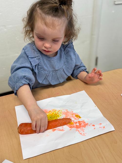 Child painting with carrot